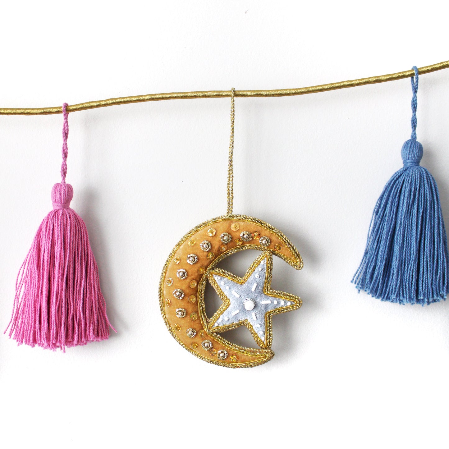 Decorative garland with a star and moon design and tassels on a white background