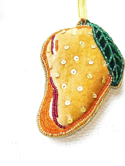 A set of handcrafted garland ornaments with symbols representing South Asian culture, including an orange mango, a blue and white rooh afza drink, a samosa, and a yellow and green jalebi.