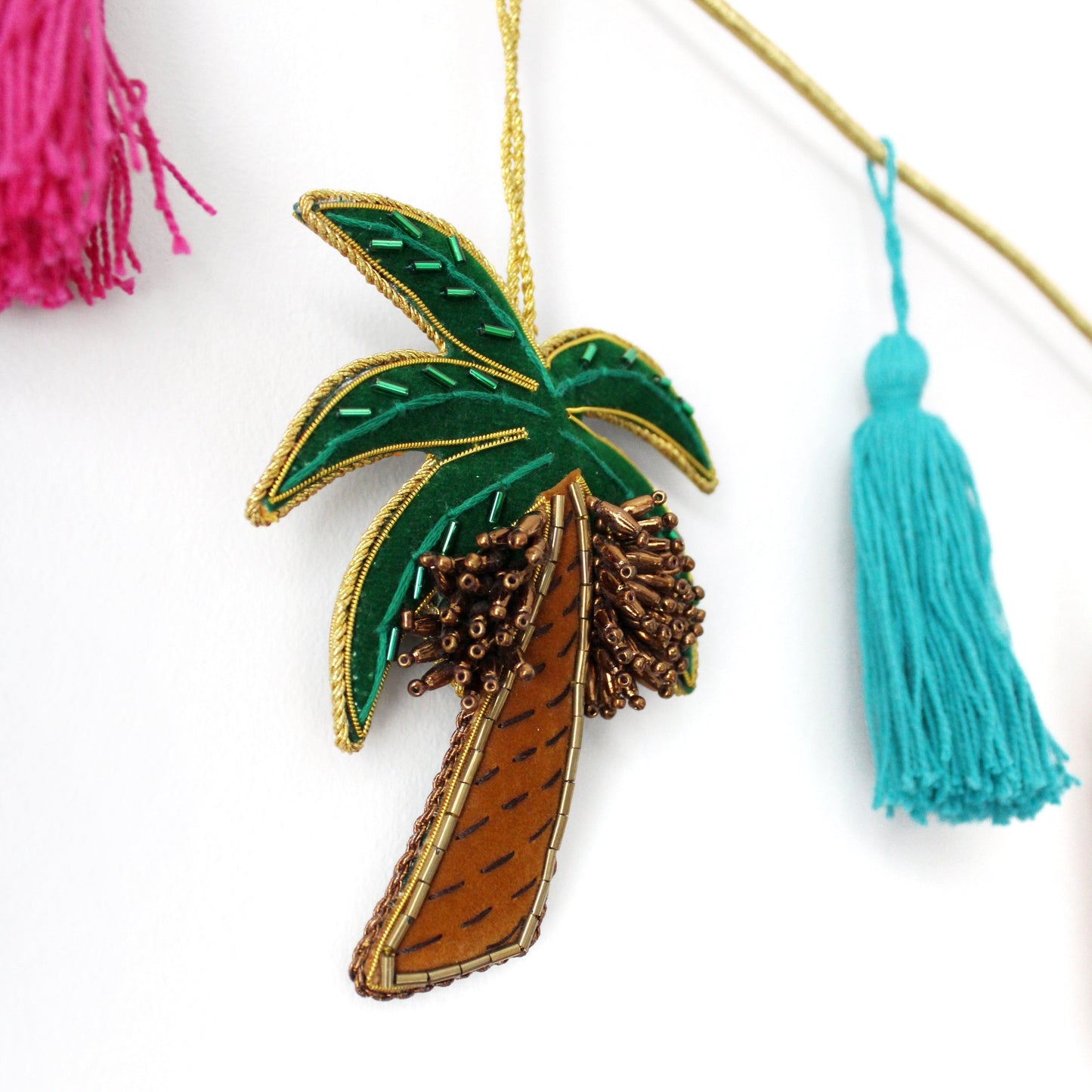 A collection of various handmade ornaments including representations of religious and cultural symbols such as the Kabaah, a mosque, a Quran, and other significant items for Muslims, along with tassels and a gold display cord.