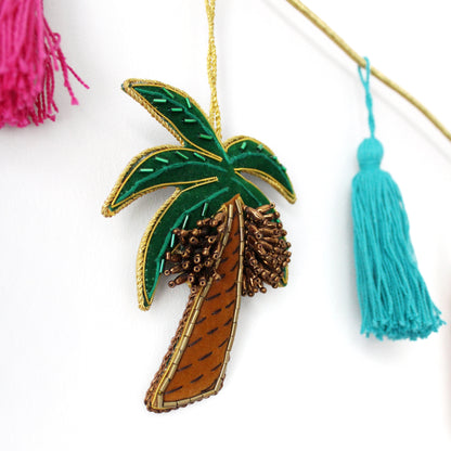 A collection of various handmade ornaments including representations of religious and cultural symbols such as the Kabaah, a mosque, a Quran, and other significant items for Muslims, along with tassels and a gold display cord.